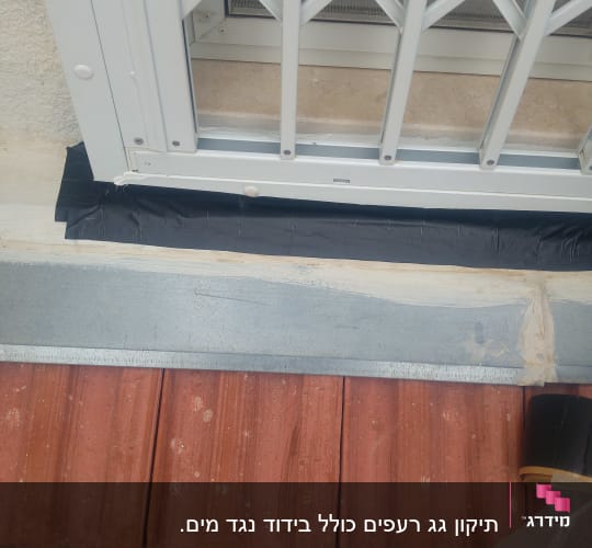 רעפים אדומים עם סרט איטום שחור ליד חלון